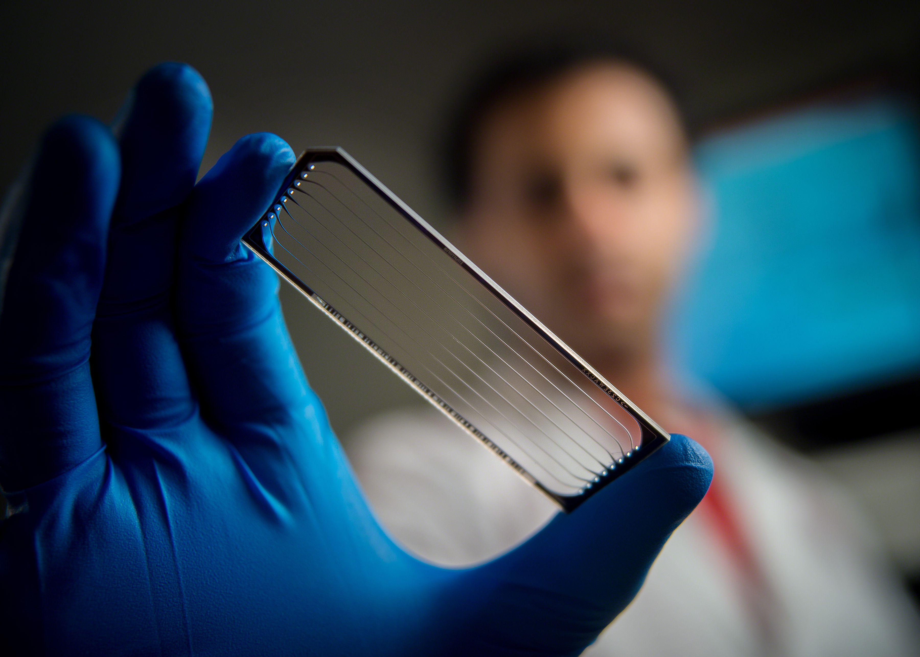 A scientist holds a flow cell used for genomic sequencing of pediatric cancers