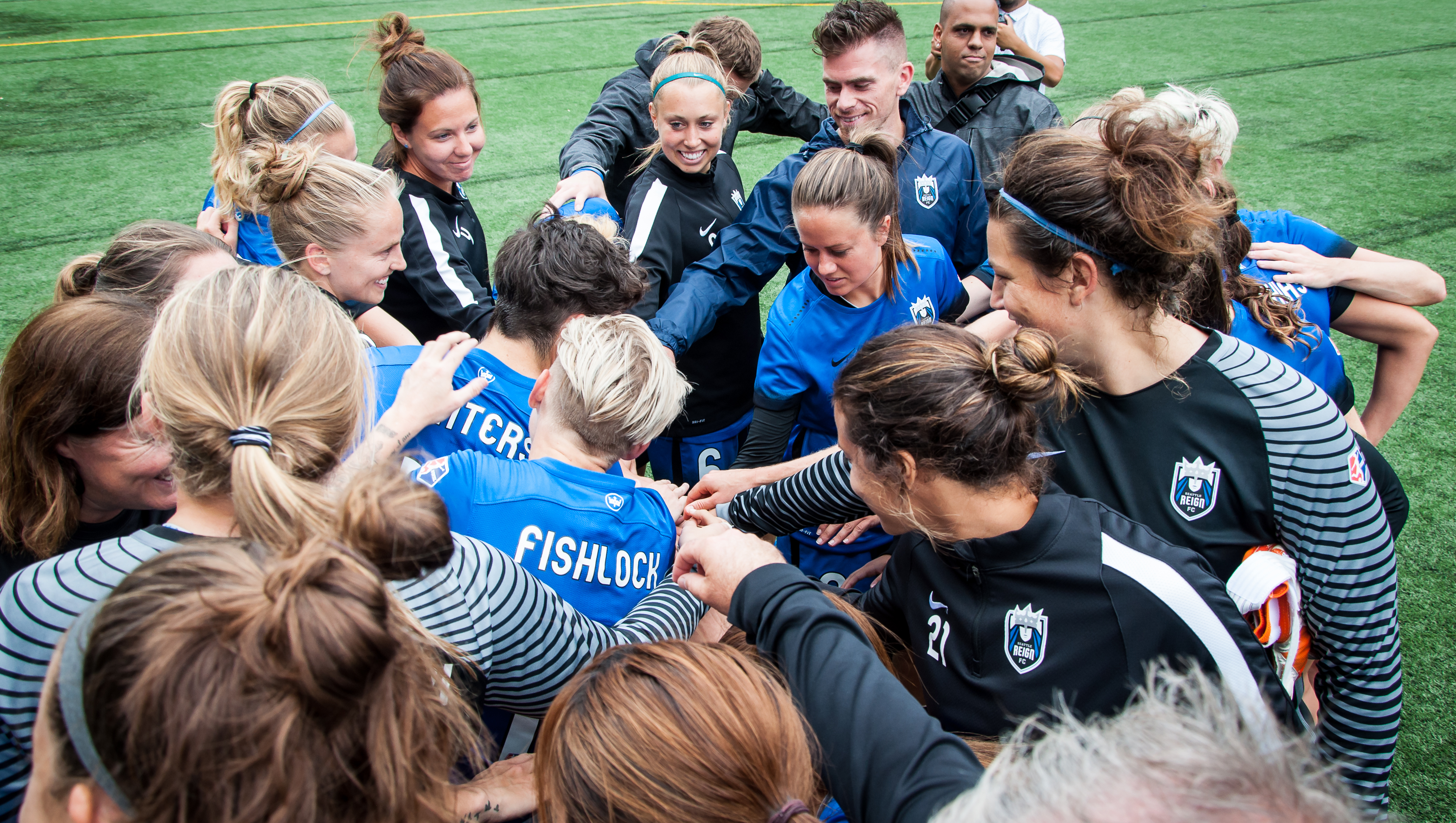 Photo of enthusiastic players and others crowd into a circle after a match