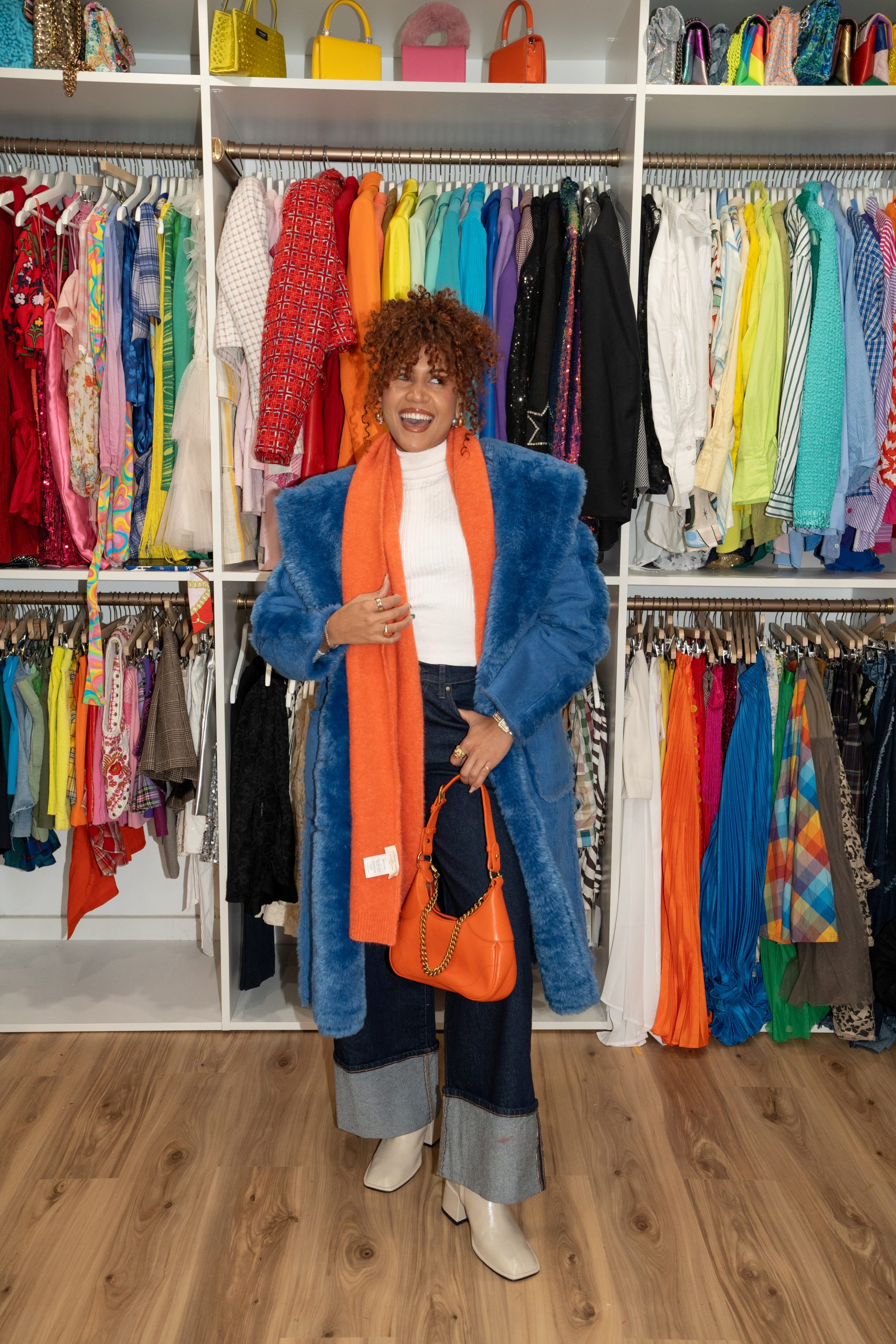 Aimee is pictured standing in front of a wall of colorful clothing.