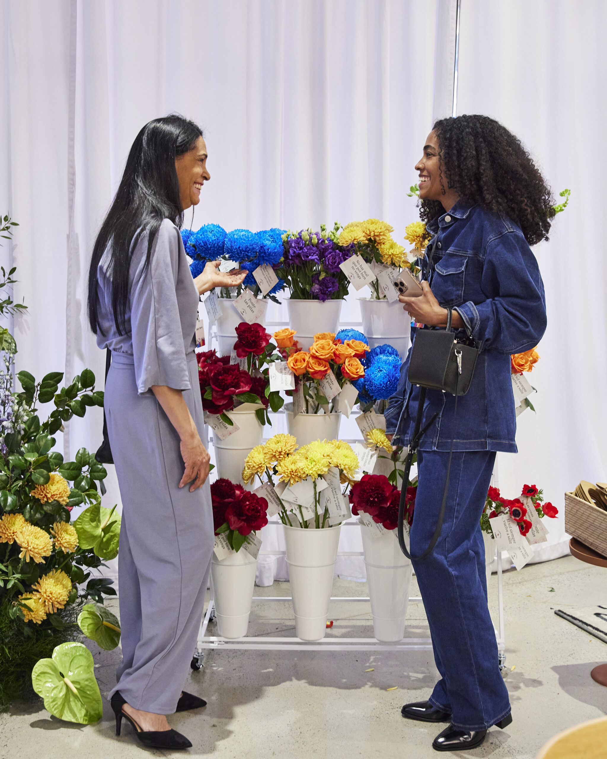 Two women smile and chat while picking out vibrant flowers from the colorful consejito floral display.
