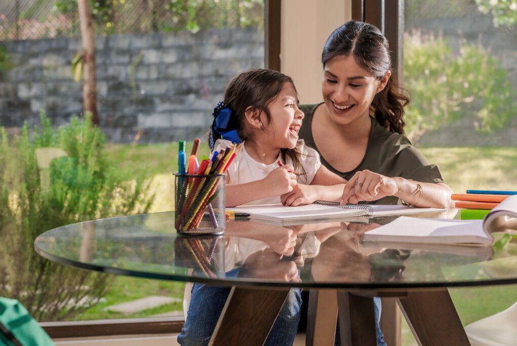 Mom happily helping her daughter study