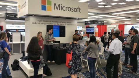 Group standing at a booth with a sign that says Microsoft.