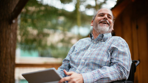 Stuart Pixley, a Senior Attorney at Microsoft who uses a wheelchair, smiles while holding a Surface