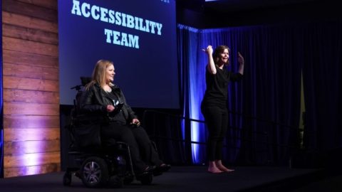 Jessica Rafuse presenting on stage at the 2019 Ability Summit. A sign language interpreter signs next to her.