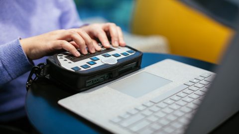 Anne Taylor, a woman who is blind, uses a braille keyboard with a Surface device.