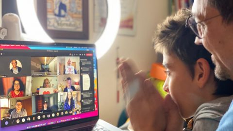 Roberto holding his son Mario while on a Microsoft Teams call with the community