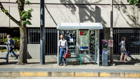 Man holding his phone while waiting for the bus