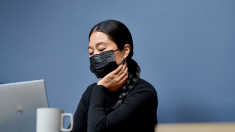 Woman wearing a mask looking pensively into her computer