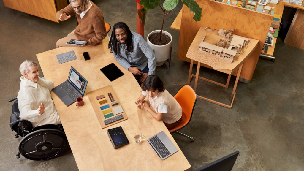 People in the conference room joining on a laptop via Companion Mode while a remote participant presents during a Microsoft Teams Room (MTR) meeting​.