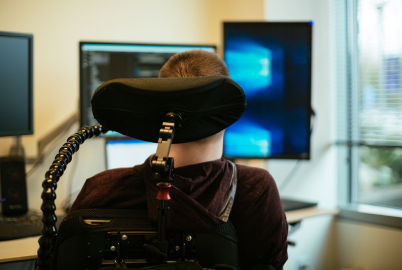 Chris Schlechty, a man who uses a wheelchair, looks at multiple monitors on his desk