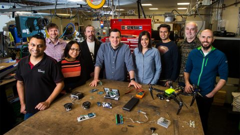 Group of people standing by a table with intelligent devices.