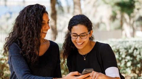 Two women outdoors looking at a mobile device
