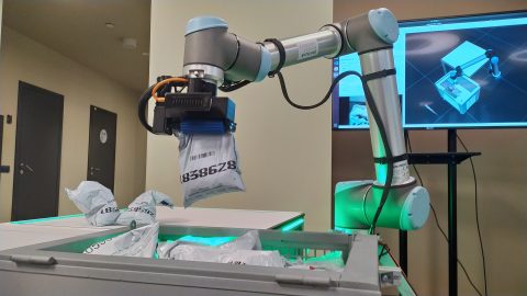 A robotic arm picks up a bag of coins