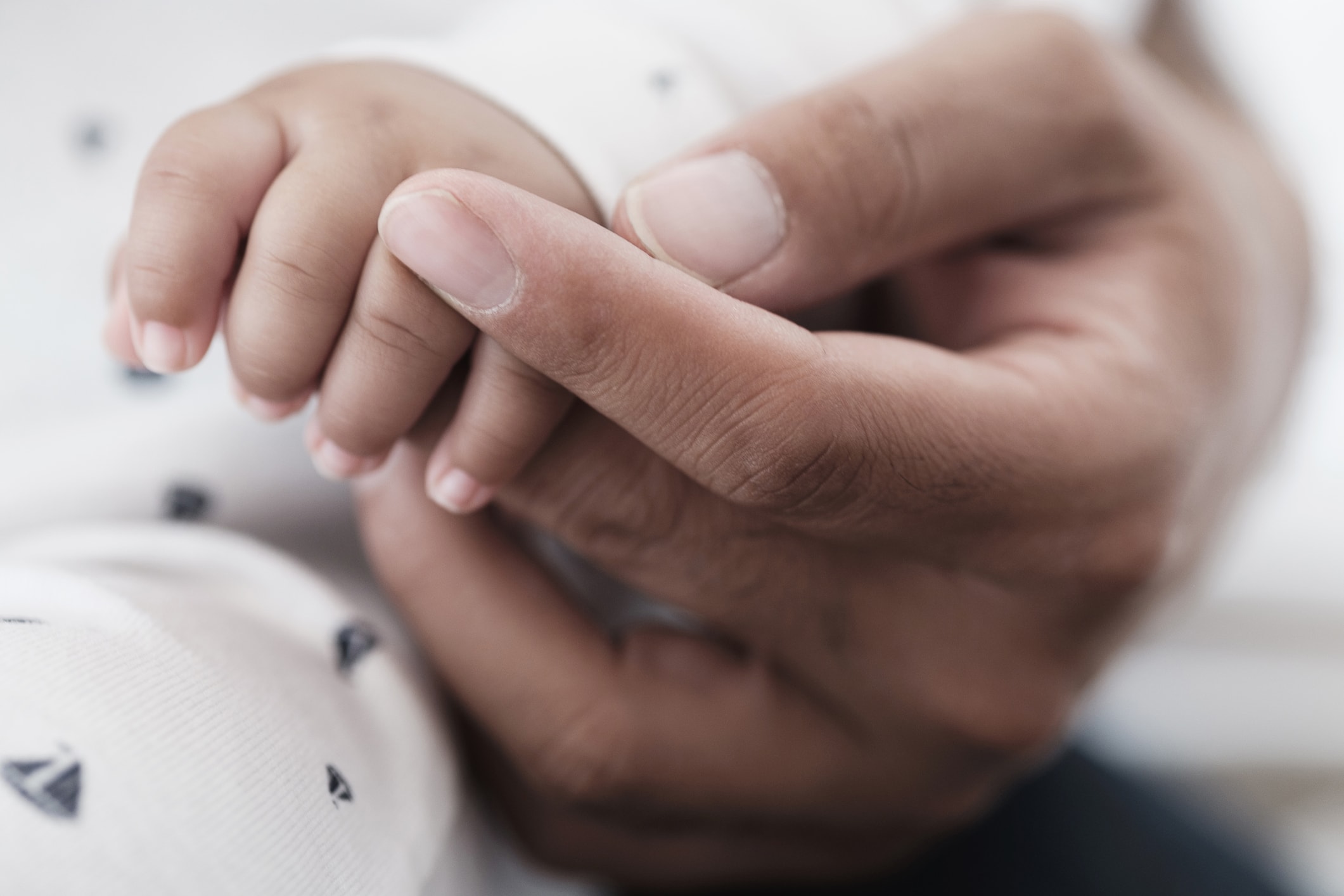 Close up of father holding hand of baby son