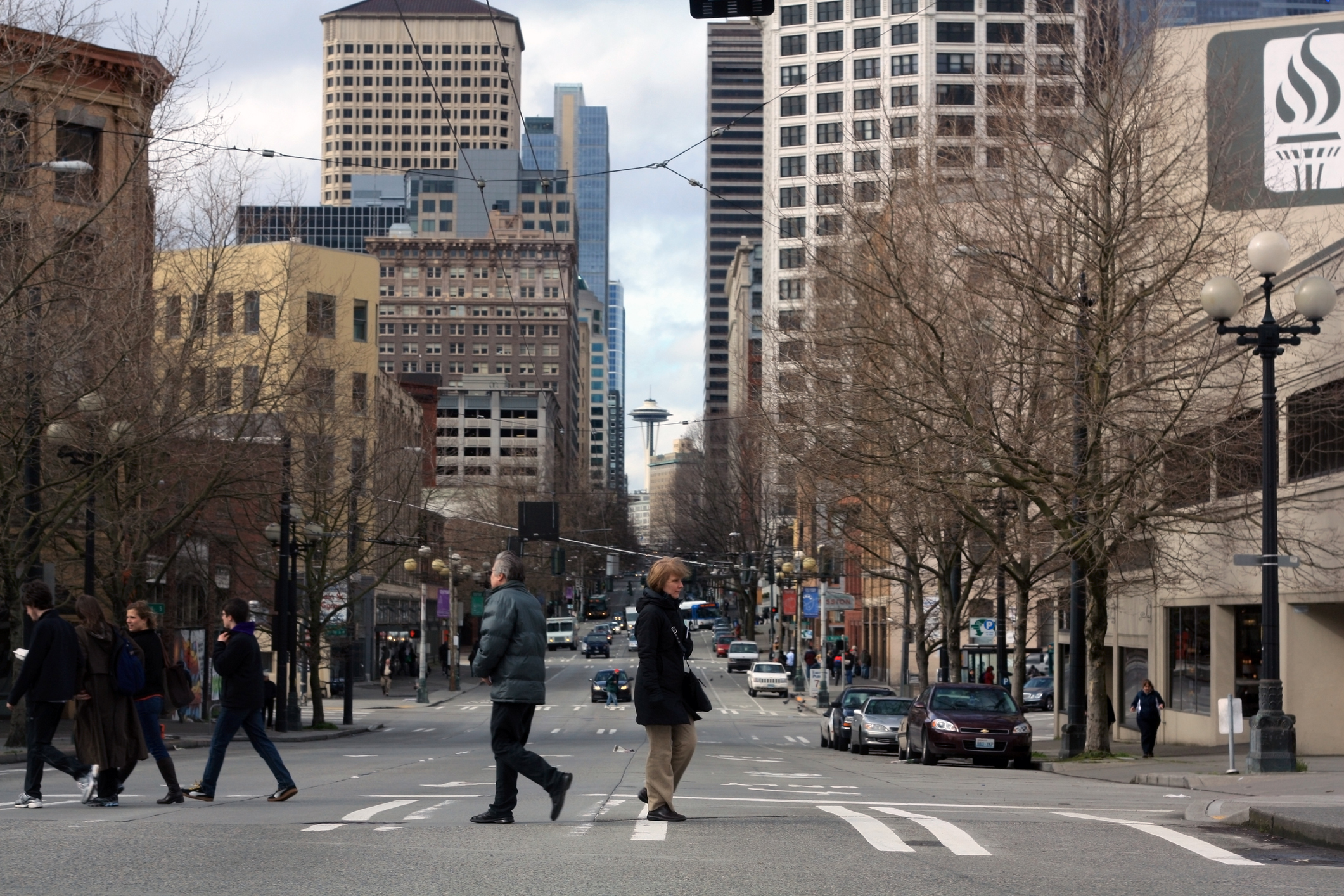 People walk across the street in Seattle with the space needle in the background