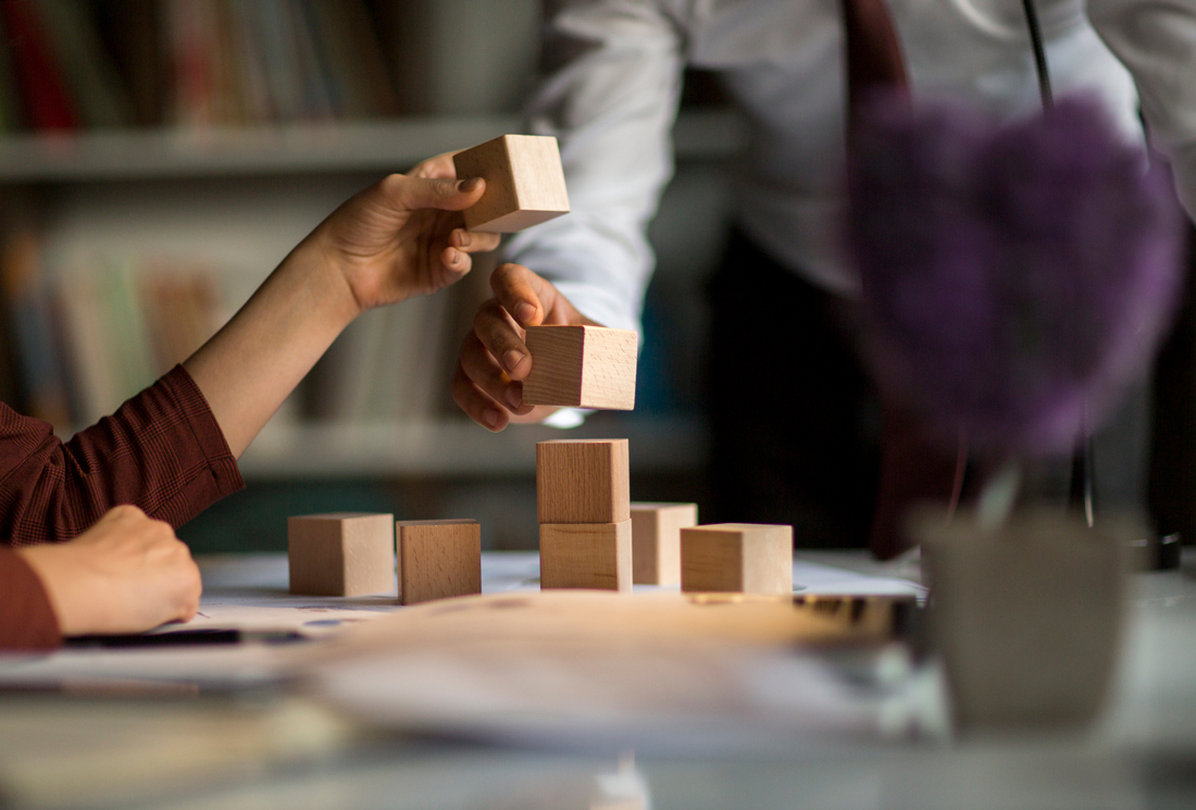 hands stacking wooden blocks