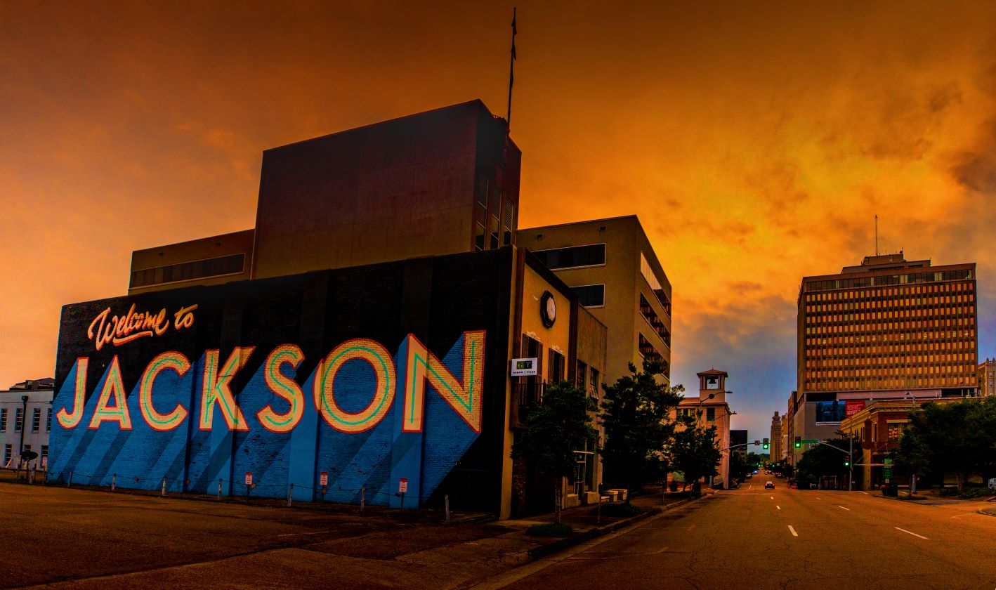 Image of a mural with the words Welcome to Jackson, against orange sky background.