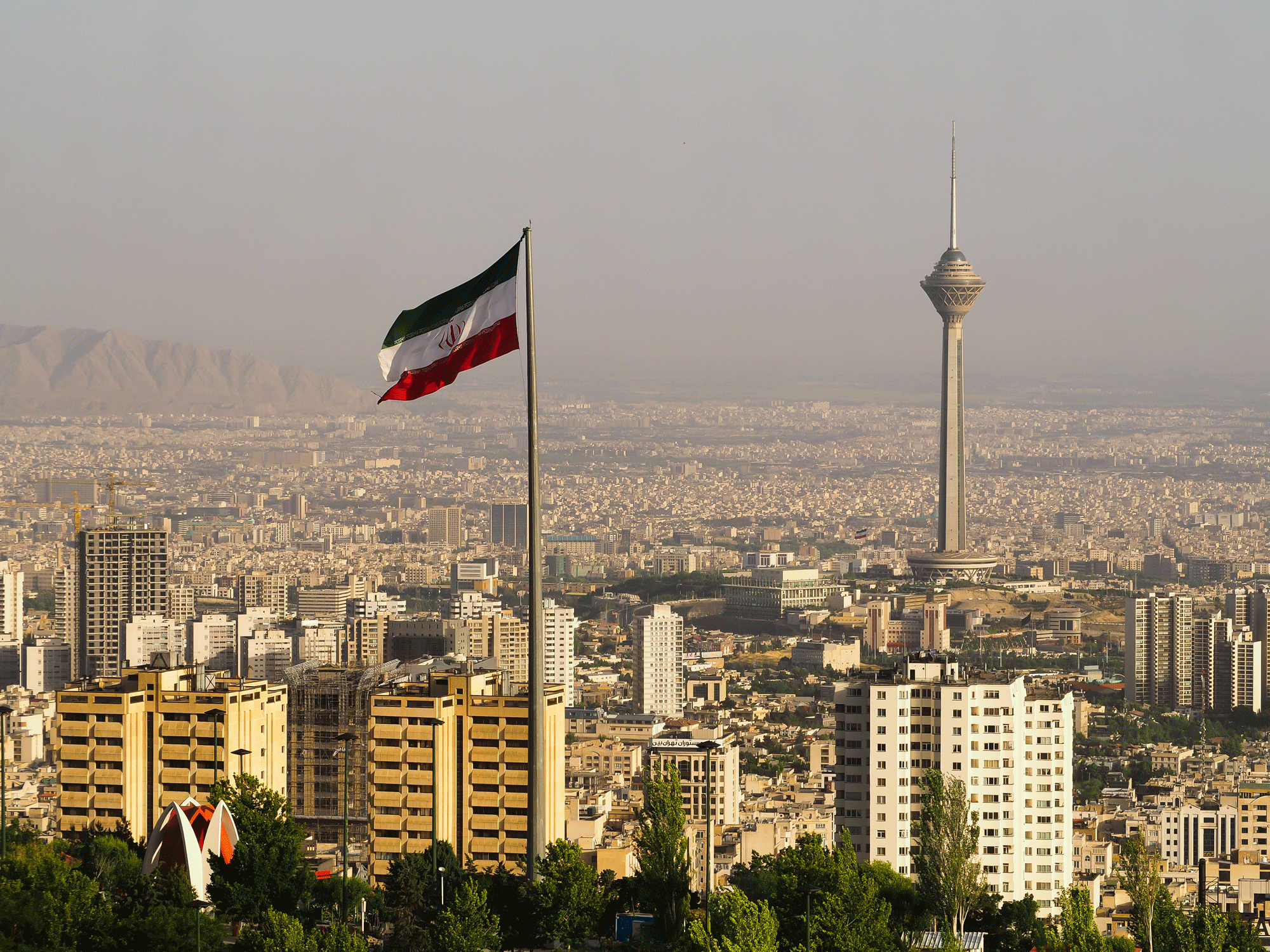 A view of Tehran, Iran, with an Iranian flag in foreground