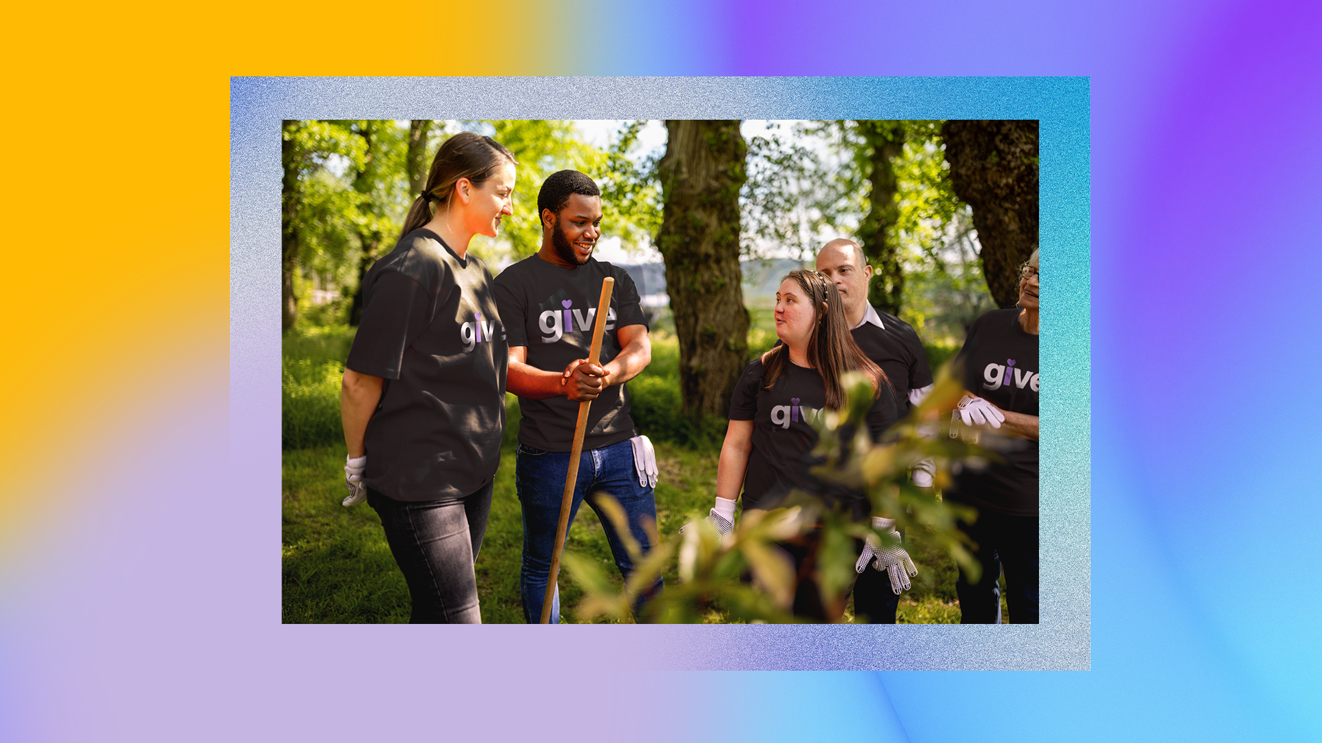 A group of people wearing black t-shirts with the word "give" printed on them are standing outdoors in a park-like setting. They appear to be engaged in a community service activity, as one person is holding a rake and others are wearing gloves. The background shows trees and greenery. The image has a colorful gradient border with shades of yellow, blue, and purple.